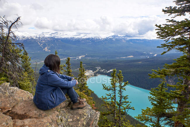 Mujer sentada en la roca y mirando al lago - foto de stock