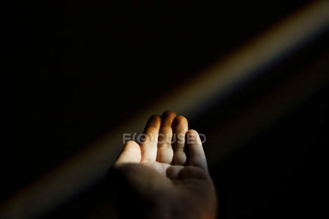 Unrecognizable female hand reaching out to a rainbow in the dark — Stock Photo
