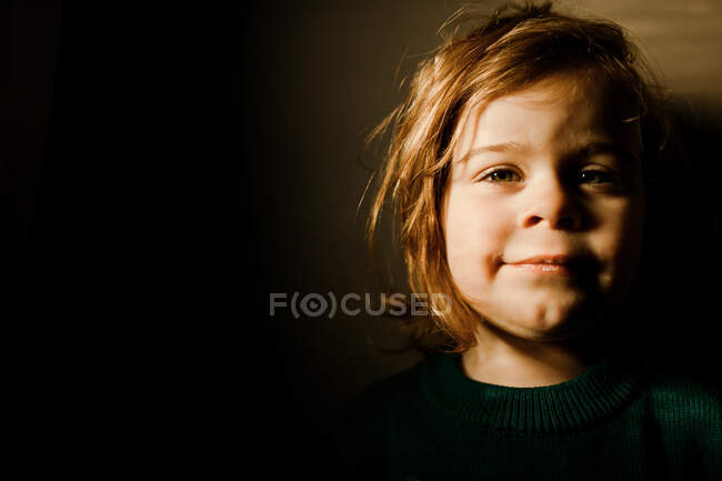 Entschlossenes Kleinkind steht im hellen Licht und lächelt — Stockfoto