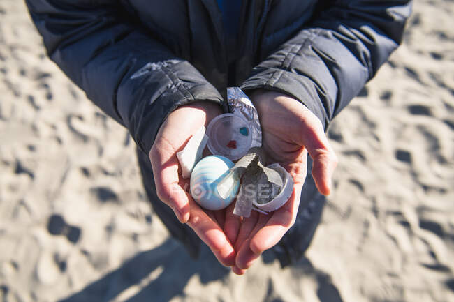 Primer plano de las manos sosteniendo residuos de basura plástica oceánica en la playa - foto de stock