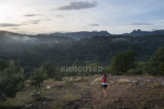 Uma mulher correndo sozinha em um trilho no início da manhã — Fotografia de Stock