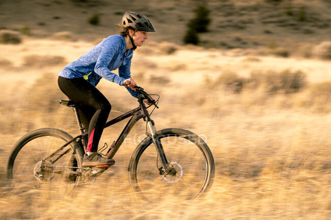 Mulher andando de bicicleta de montanha downhill durante o pôr do sol — Fotografia de Stock
