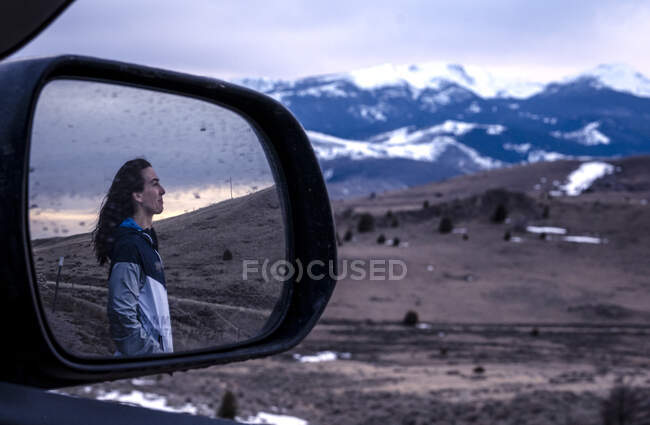 Jeune femme regardant le coucher du soleil dans les montagnes reflété dans le miroir — Photo de stock