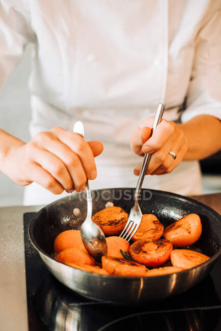 Chef cooking fried apricots in a frying pan on background, close up — Stock Photo