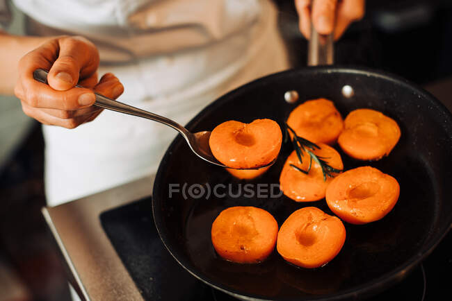 Koch kocht gebratene Aprikosen in einer Pfanne auf dem Hintergrund, Nahaufnahme — Stockfoto