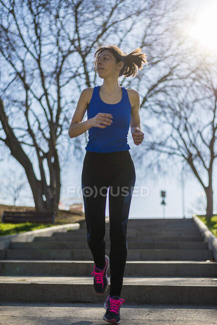 Portrait of a woman running on staircase outdoors in a park — Stock Photo