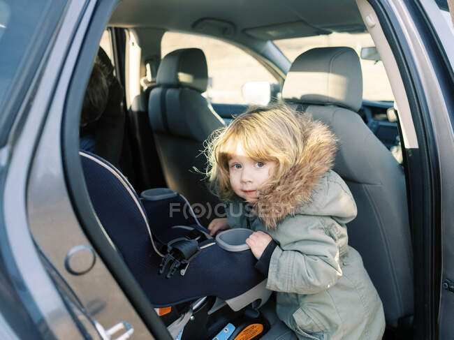 Kleines Mädchen steigt in ihren Autositz. — Stockfoto