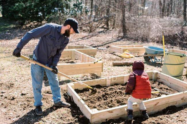 Un père et son fils préparent des lits de jardin surélevés au début du printemps. — Photo de stock