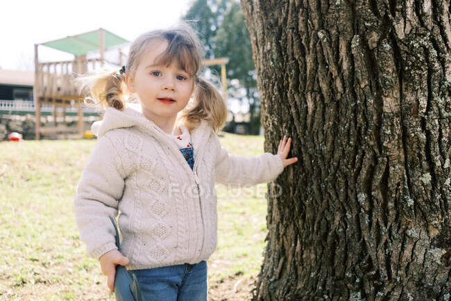 Petite fille mignonne tout-petit avec des queues de porc jouant dans la cour. — Photo de stock