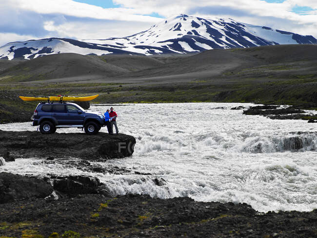 Пара карт чтения перед их индивидуальным внедорожником в Исландии — стоковое фото