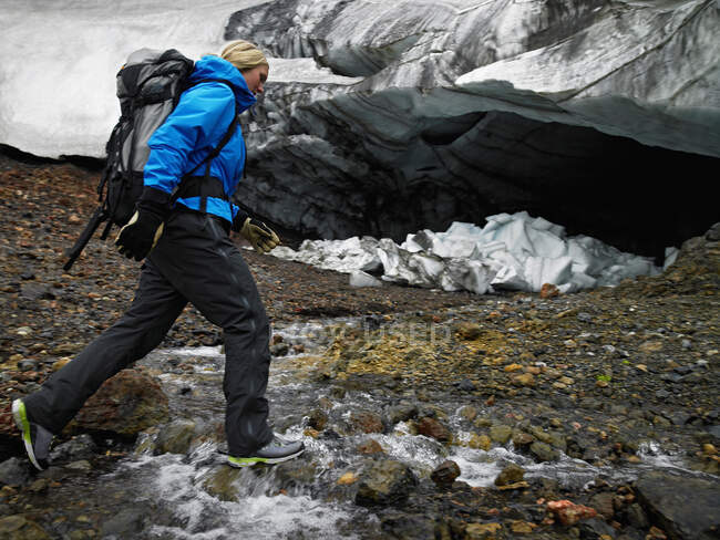 Mujer joven cruzando el río en Hrafntinnusker en Islandia - foto de stock
