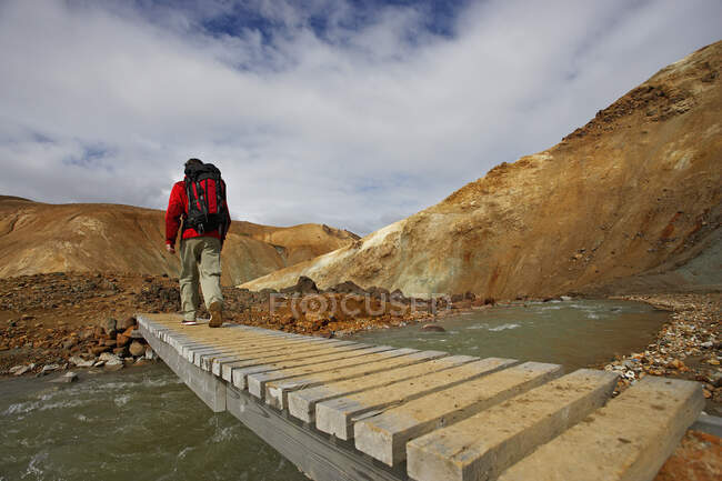 Caminhante atravessando ponte de madeira nas terras altas da Islândia — Fotografia de Stock