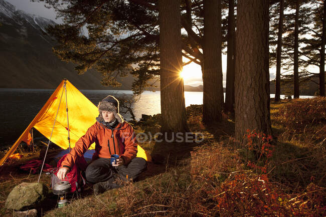 Mann bereitet Heißgetränk in einfachem Camp im British Lake District zu — Stockfoto