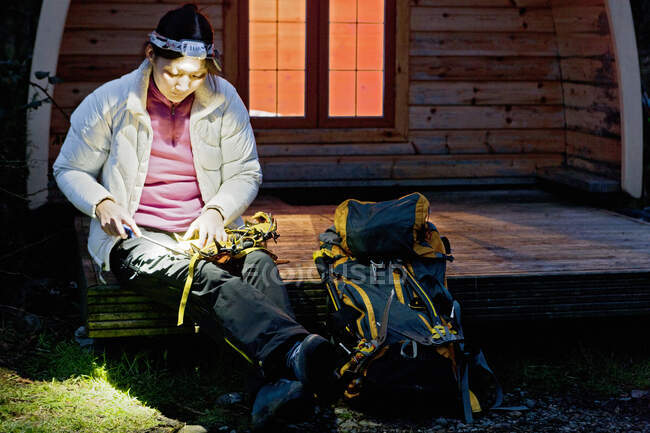 Woman sharpening her crampons in front of camping pod in the UK — Stock Photo