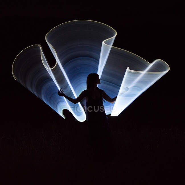 Силуэт женщины через синий свет на закате в — стоковое фото