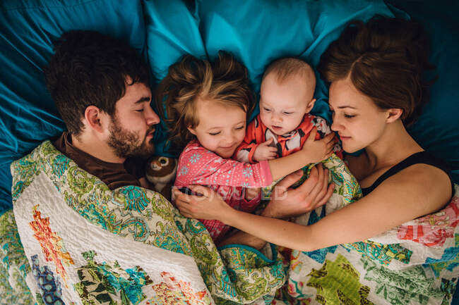 Мама і тато і діти сплять і обіймаються в ліжку вранці — стокове фото