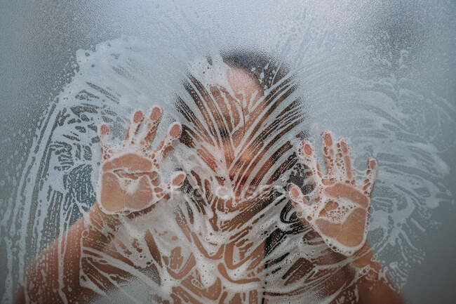 Close up of child in shower playing with soap on door — Stock Photo
