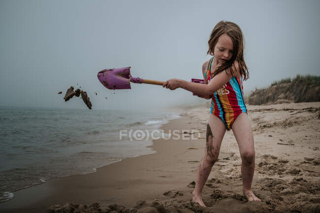 Niña jugando con un barco de juguete en la playa - foto de stock