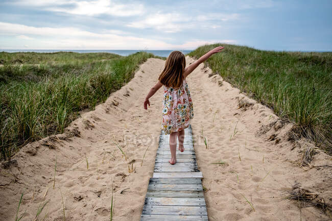 Дівчина в білій сукні йде по шляху на пляжі — стокове фото