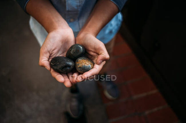 Retrato de un niño sosteniendo rocas en sus manos - foto de stock