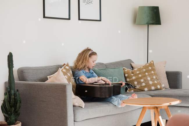 Giovane ragazza seduta a casa a suonare la chitarra — Foto stock