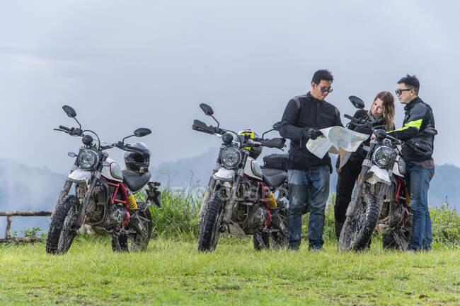 Три друзі дивляться на карту під час подорожі на мотоциклі — стокове фото