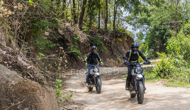 Due amici cavalcando le loro motociclette scrambler attraverso forrest — Foto stock