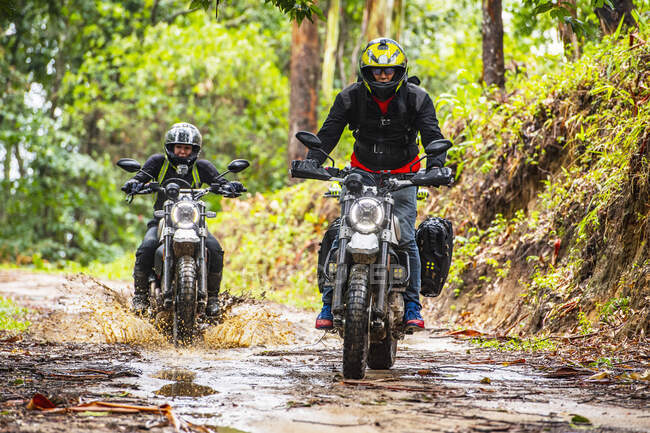 Two friends riding their scrambler motorcycles through forrest — Stock Photo