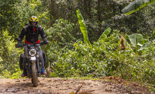 Homme chevauchant sa moto de type brouilleur à travers la forêt — Photo de stock