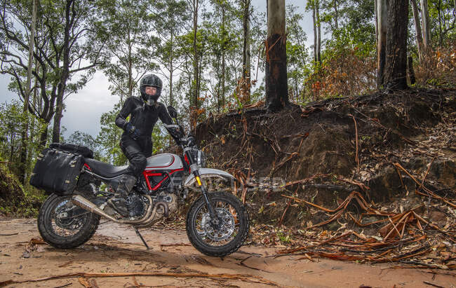 Mujer posando en su moto tipo scrambler en el bosque tailandés - foto de stock