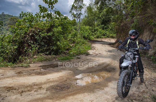 Woman riding her scrambler type motorcycle on muddy road in Thailand — Stock Photo