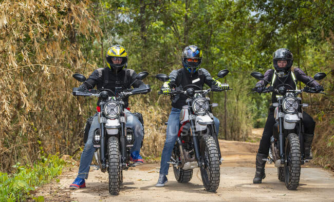 Three friends riding their scrambler motorcycles through forrest — Stock Photo