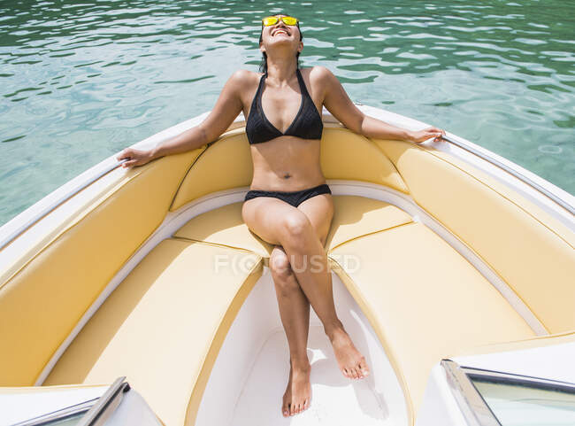 Woman sunbathing at the bow of a motor boat at a tropical island — Stock Photo