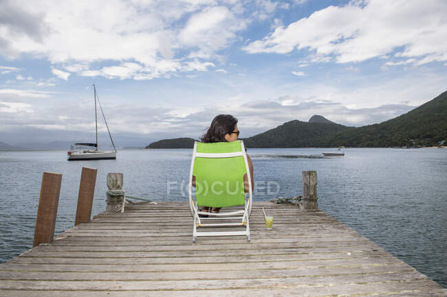Mujer relajándose en muelle en la isla tropical de Ilha Grande - foto de stock