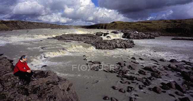 Frau bewundert Wasserfall auf dem Fluss in Island — Stockfoto
