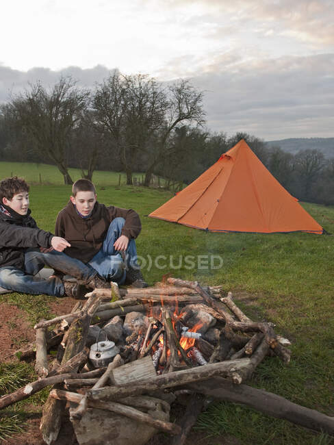 Dos chicos sentados en una fogata en Gales del Sur - foto de stock