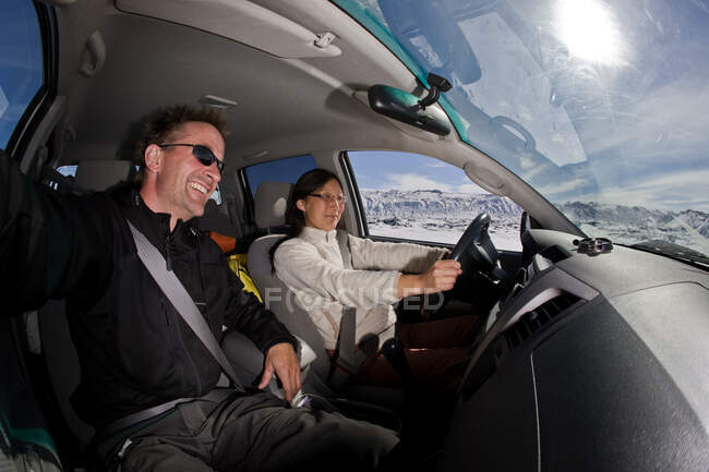 Casal dirigindo através de paisagem nevada na Islândia — Fotografia de Stock