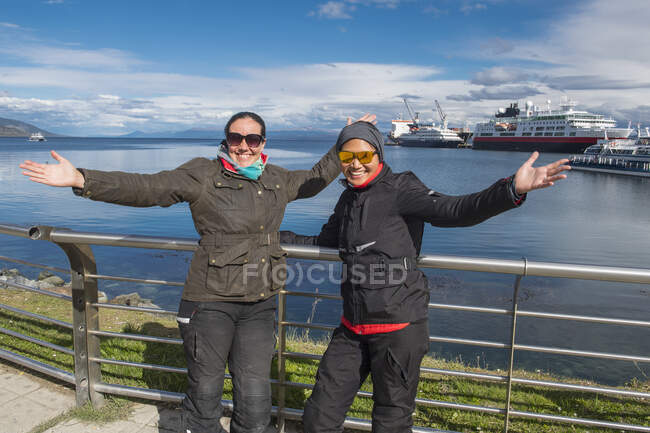 Two women in motorbike clothes posing at the harbour of Ushuaia — Stock Photo