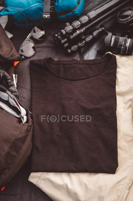 T-shirt preta em uma tenda cercada por foto e equipamento de acampamento — Fotografia de Stock