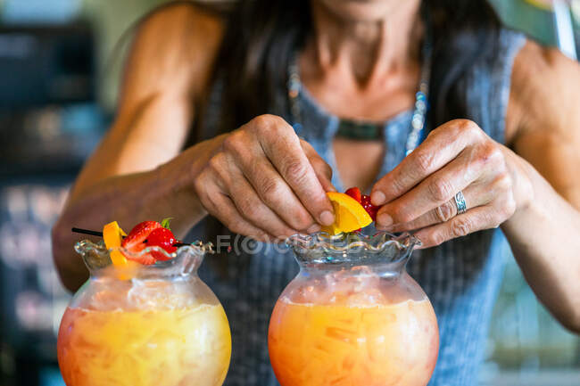 Primer plano de las manos de una mujer de mediana edad haciendo bebidas con fruta - foto de stock