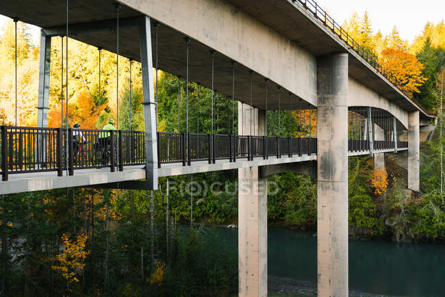 Pareja de bicicletas a caballo a través del puente con colores de otoño - foto de stock
