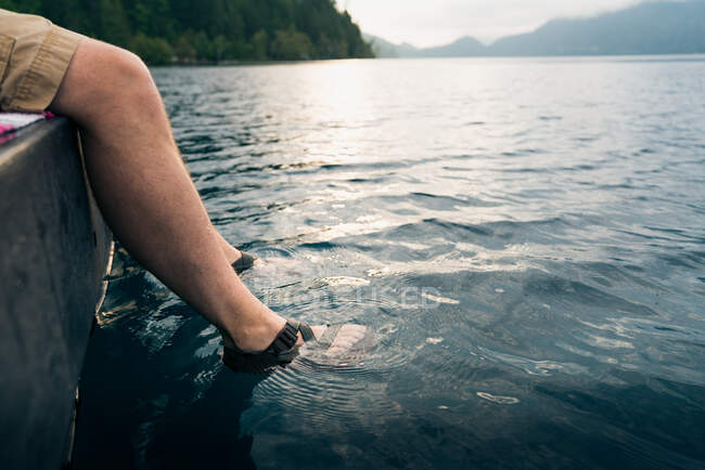 Pés de homem em sandálias mergulhadas no lago — Fotografia de Stock