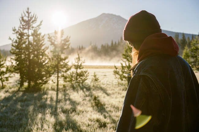 Femme randonnée au lever du soleil près de montagne brumeuse — Photo de stock