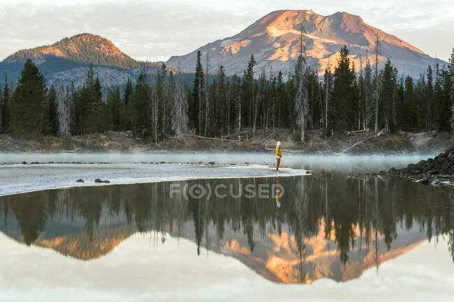 Junge Frau blickt auf einen Berg, der sich in einem See spiegelt — Stockfoto