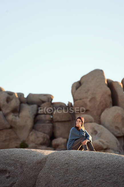 Jovem mulher sentada em rochas contemplando — Fotografia de Stock