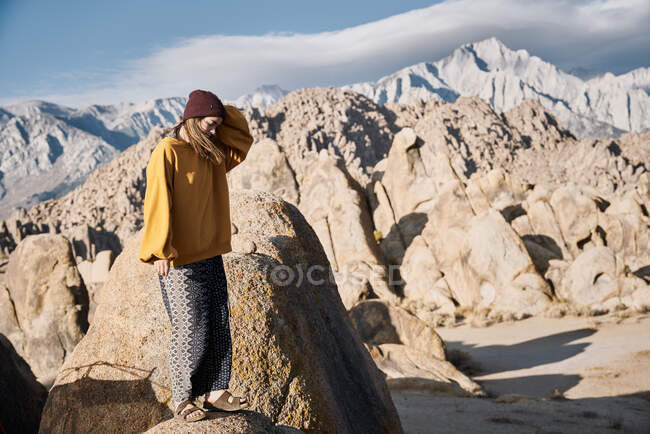 Femme debout sur le rocher dans le vent près des montagnes — Photo de stock