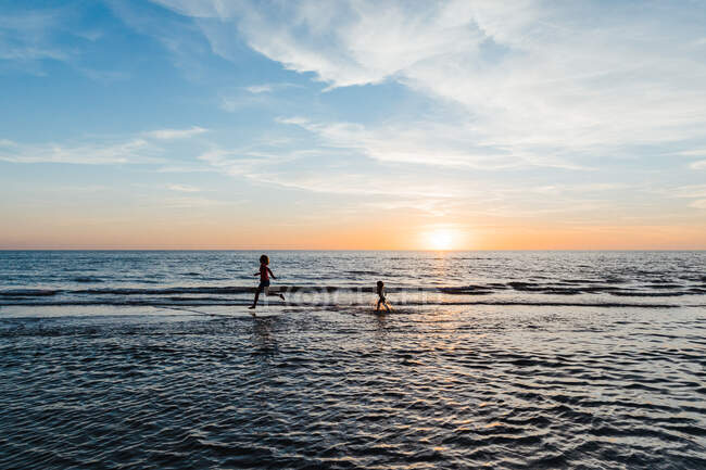 Жінка і дитина бігають у мілководді пляжу Флориди на заході сонця — стокове фото