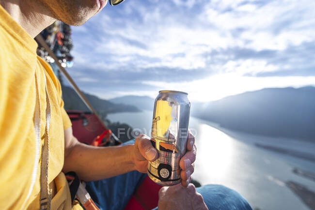 Homem bebendo e segurando lata de cerveja ao pôr do sol em um portaledge Squamish — Fotografia de Stock