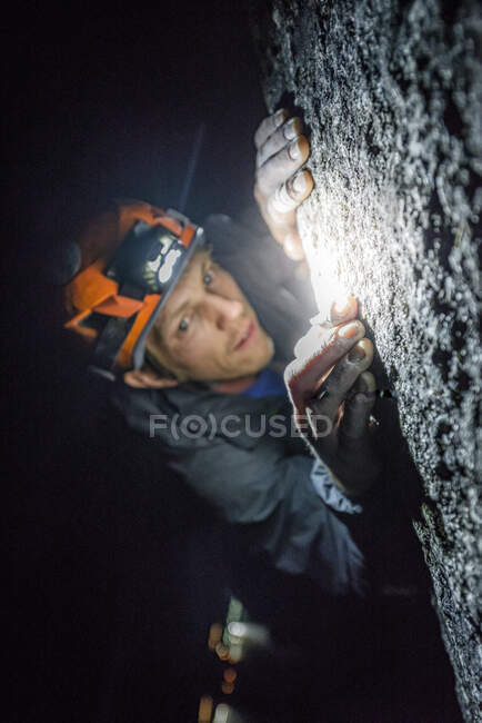 Top view man rock climbing at night above the sea and highway — Stock Photo
