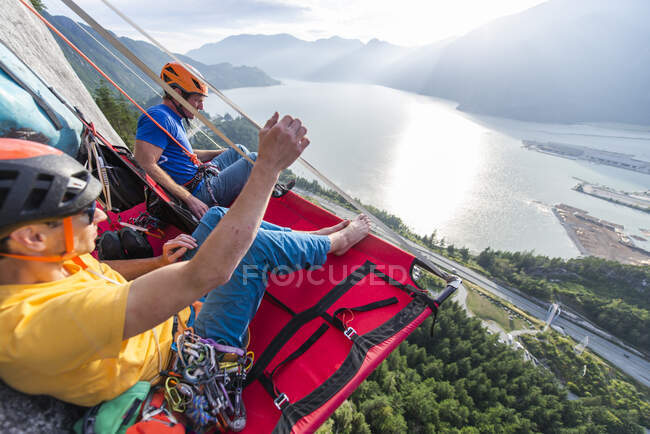 Two men sitting on a portaledge enjoying sunset and view in Squamish — Stock Photo